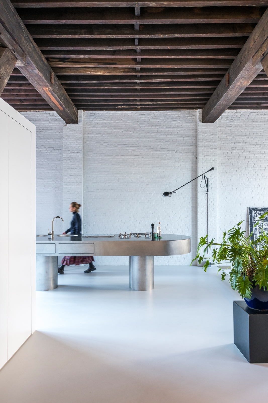 Seamless pale mineral floor beneath the original timber structure of an Antwerp loft